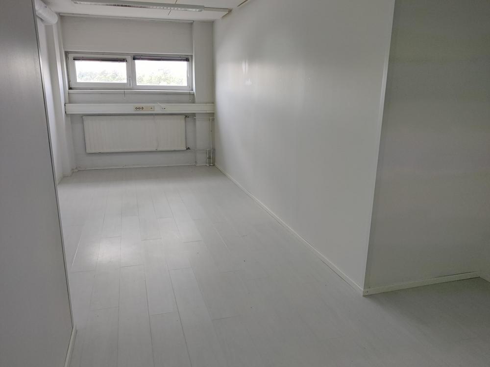 Kuva tyhjästä toimitilasta kahdella ikkunalla. Huone on väriltään valkoinen.
